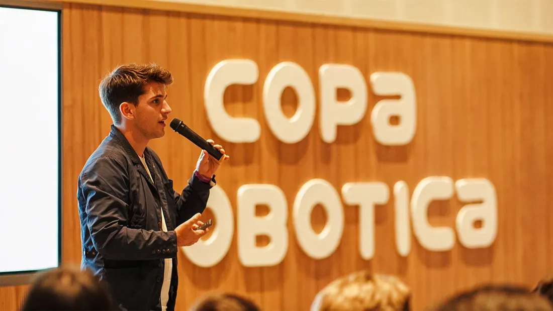 Orador presentando en el escenario del Educational Technology Summit, con el isotipo de la Copa Robótica de fondo